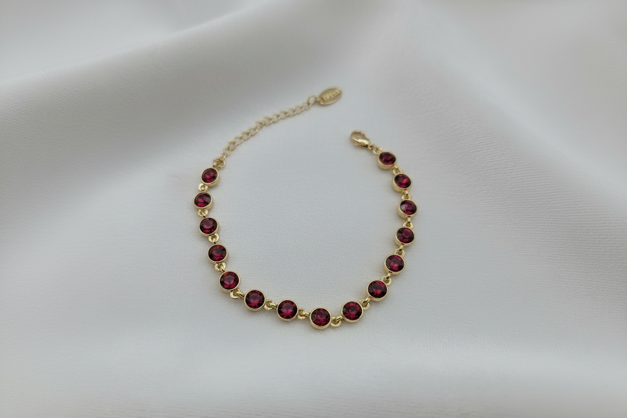 Armband med röda stenar på vit sammetsbakgrund