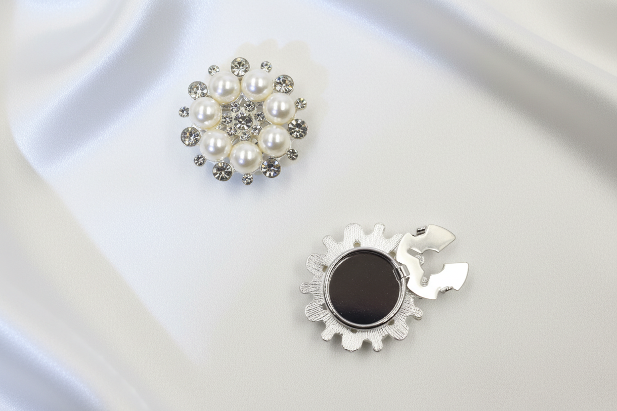 Pärl- och kristallbroscher på vit silkesbakgrund