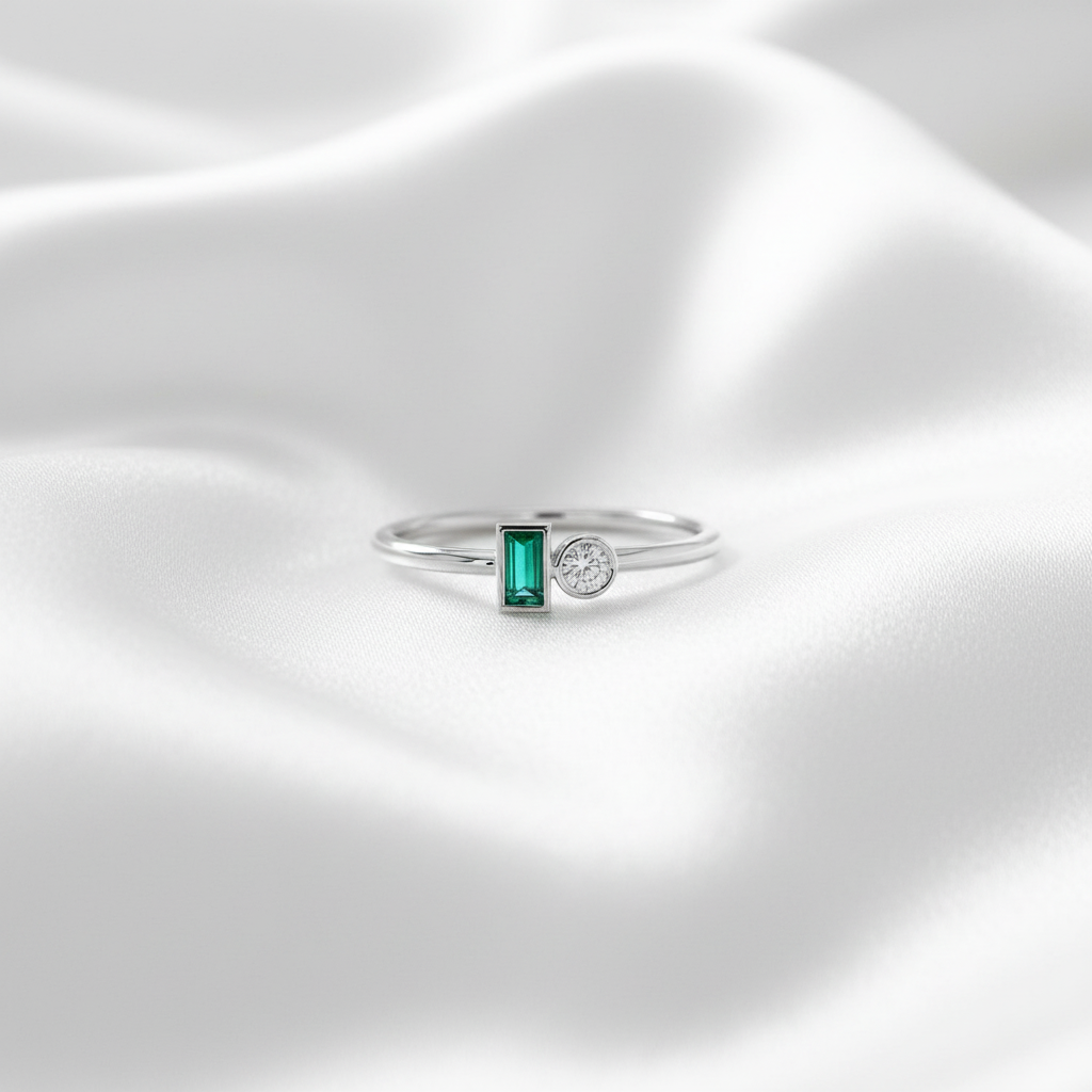 Silverring med smaragd och diamant på vit silkesbakgrund