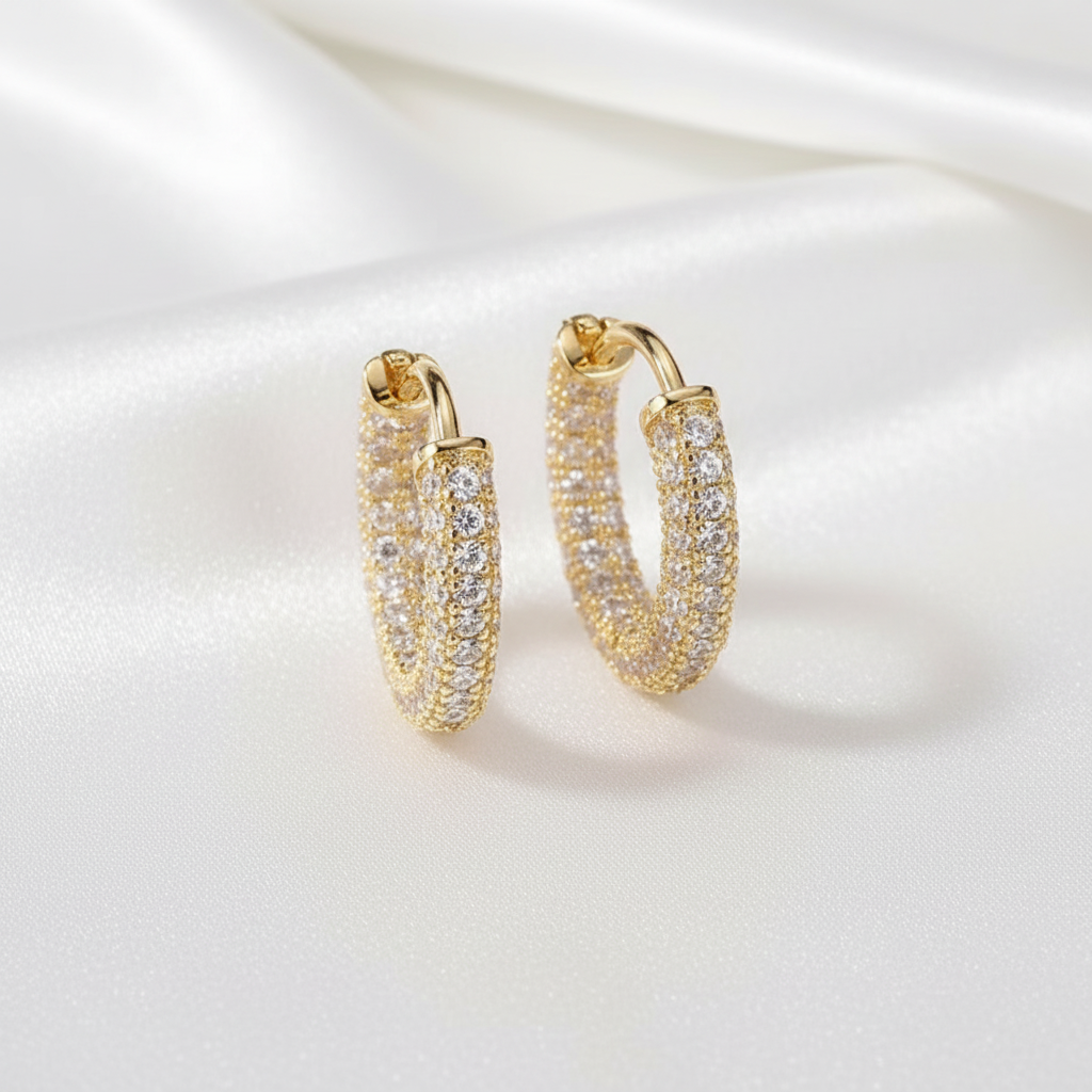 Guldpläterade örhängen med zircon på vit silkesbakgrund