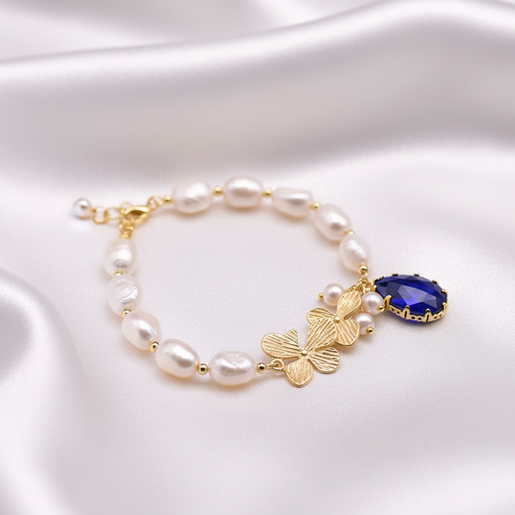 Pärlarmband med fjäril och droppformat hänge på vit silkesbakgrund